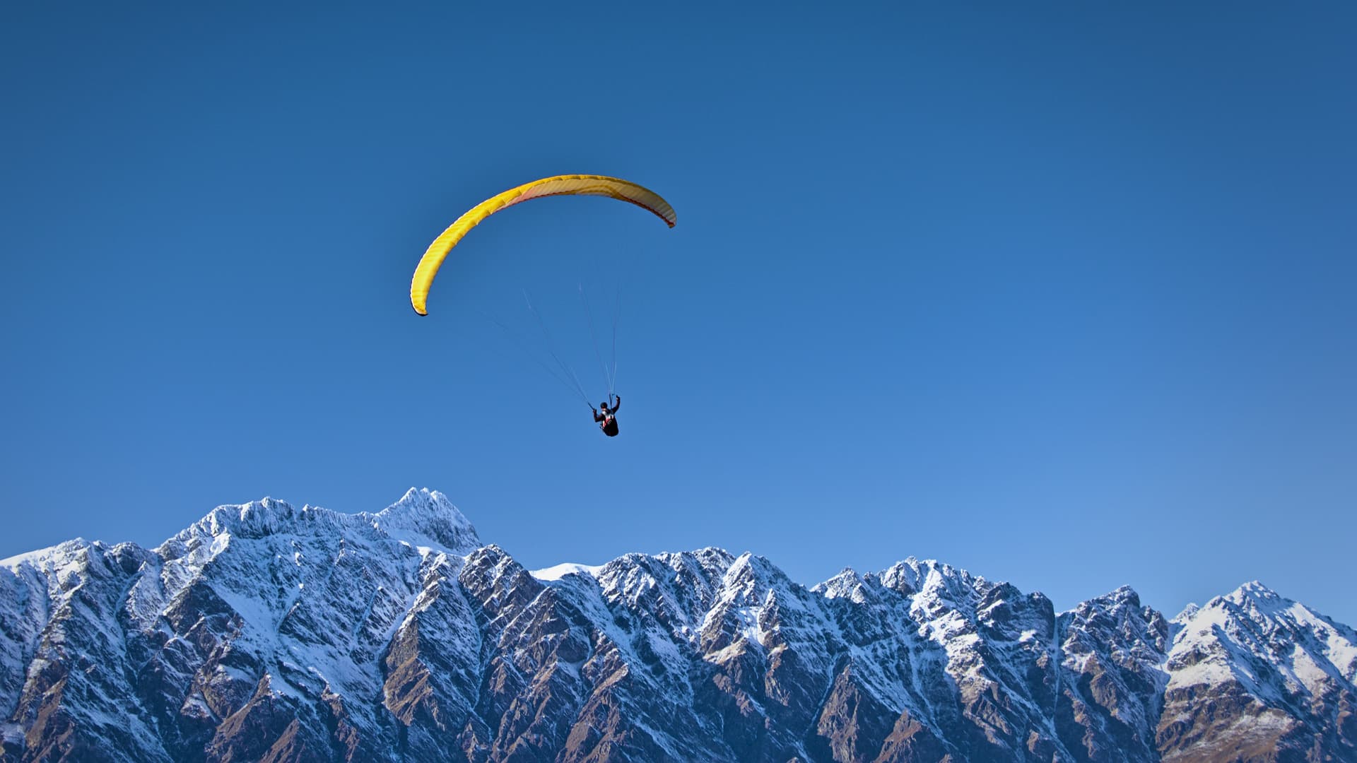 Man soaring above mountains while paragliding